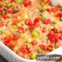 Close up looking at a Taco Bell Mexican Pizza Casserole in the baking dish, garnished with fresh toppings.