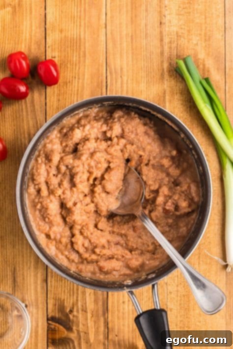 Cooked refried beans thinned with water, simmering in a pan.