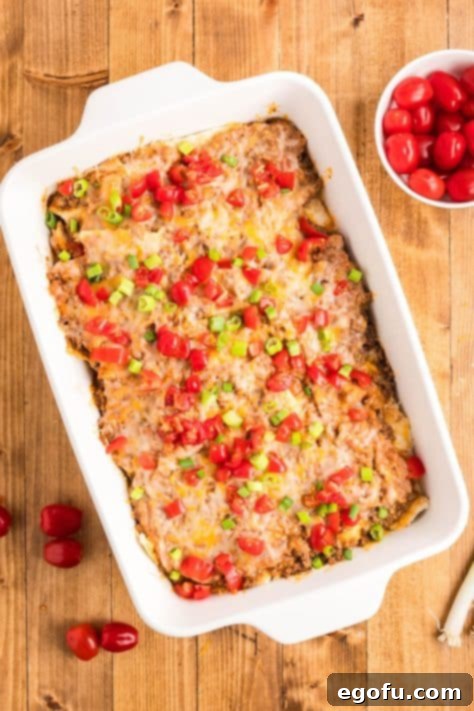 Garnished Mexican pizza casserole, topped with fresh diced tomatoes and green onions, ready to serve.