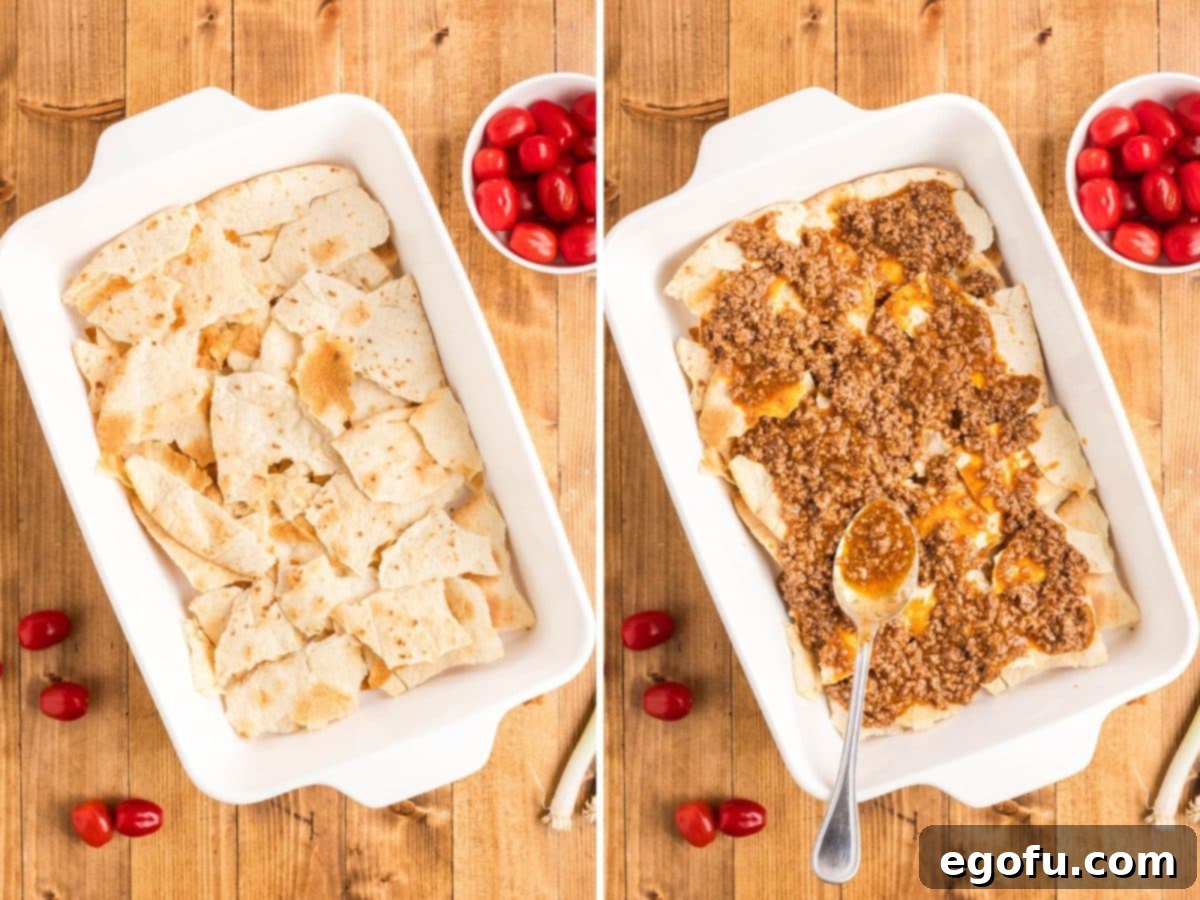 The first layer of broken tortilla shells and half of the seasoned ground beef mixture in a 9x13-inch baking dish.