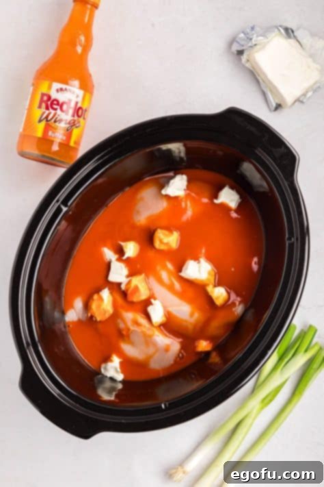 Chicken breast, cubed cream cheese, and hot sauce in the Crock pot.