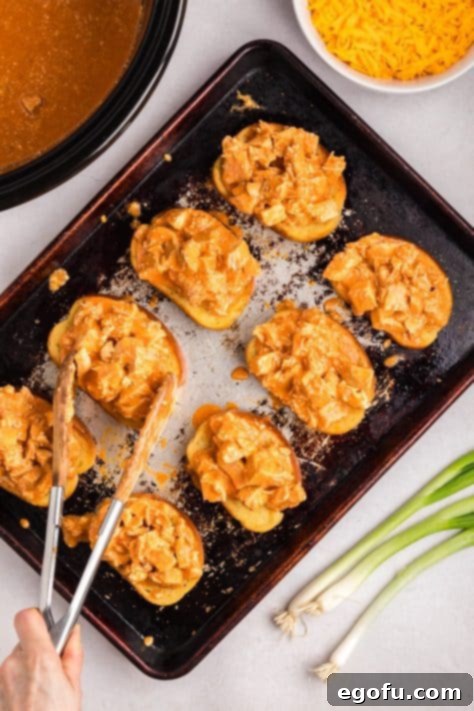 Chicken mixture being placed on Texas Toast on a baking dish.