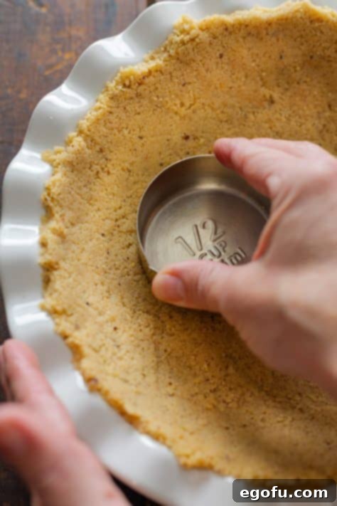 Cookie crumb crust being added to a pie plate.