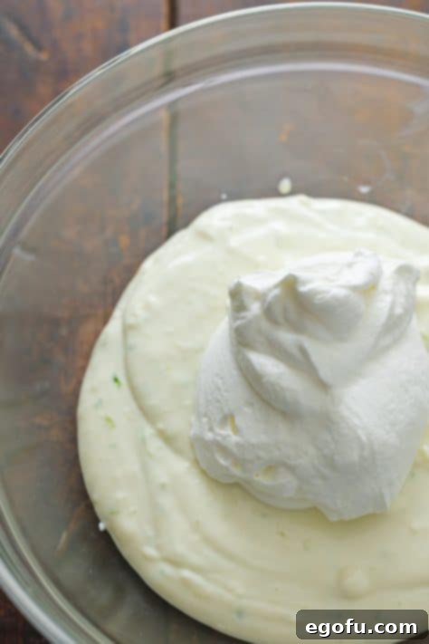 Whipped cream being added to a pie filling, showcasing the gentle folding technique.