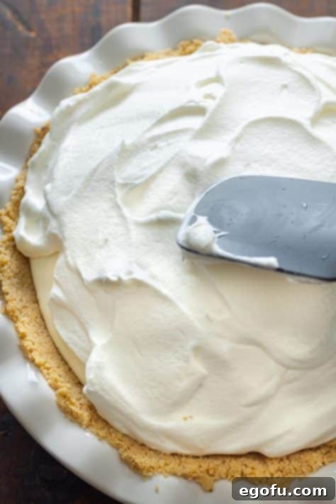 A finished Key Lime Cream Pie, topped with whipped cream, chilling in the refrigerator.