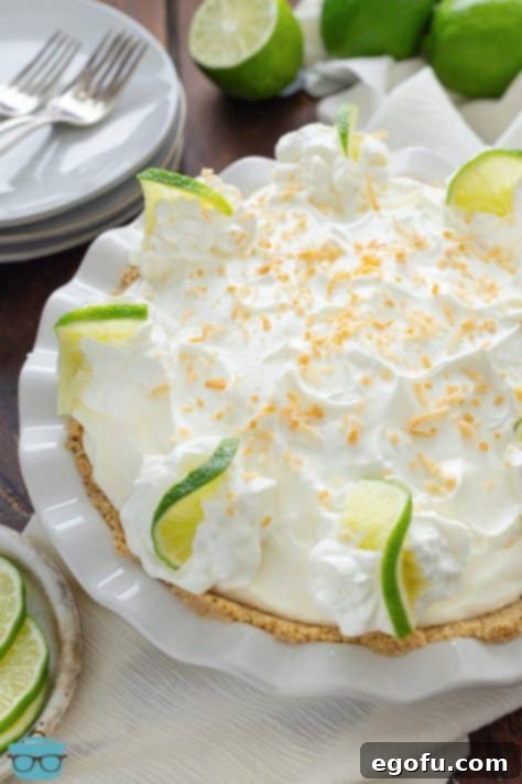 An unsliced, beautifully garnished Key Lime Cream Pie, showcasing the toasted coconut topping.