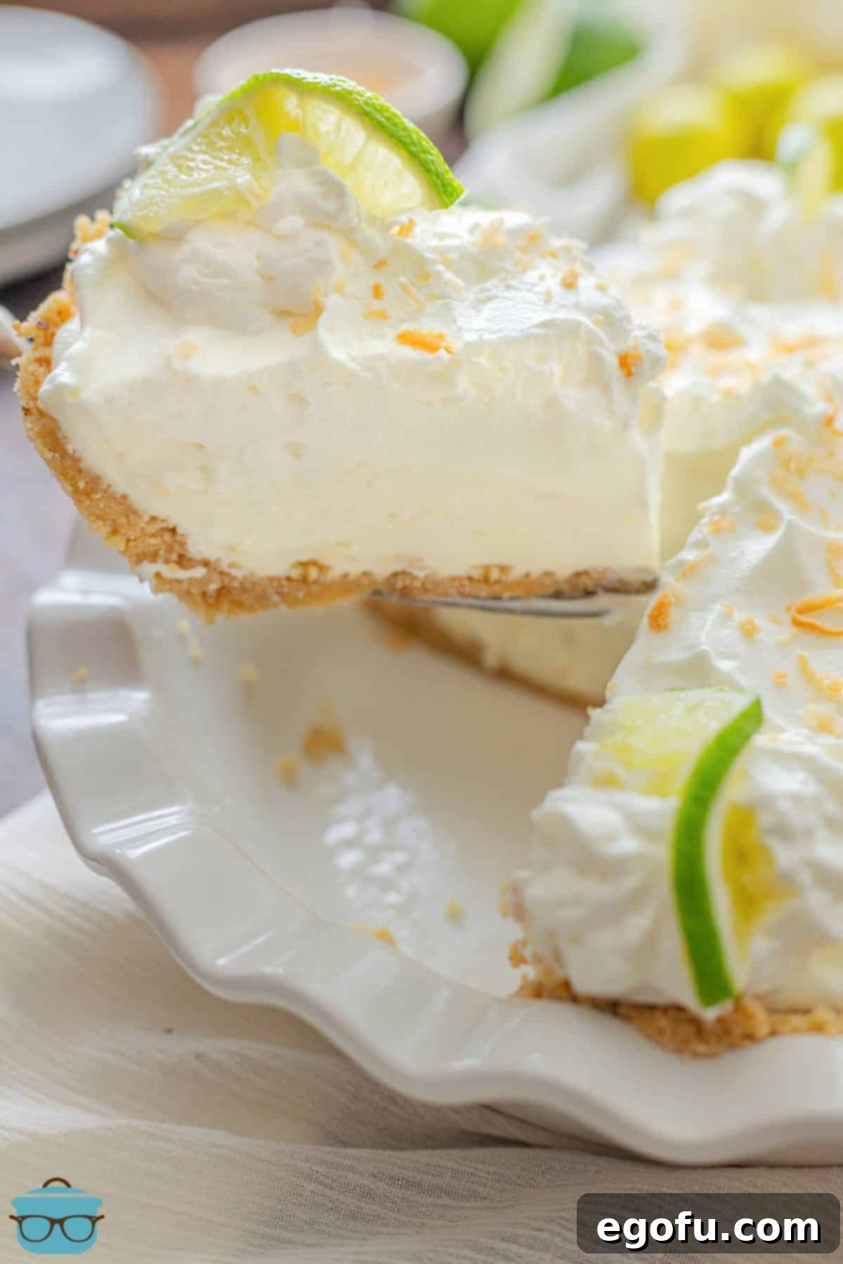 A perfectly portioned slice of Key Lime Cream Pie being carefully removed from the rest of the pie, showcasing its creamy layers and crumbly crust.