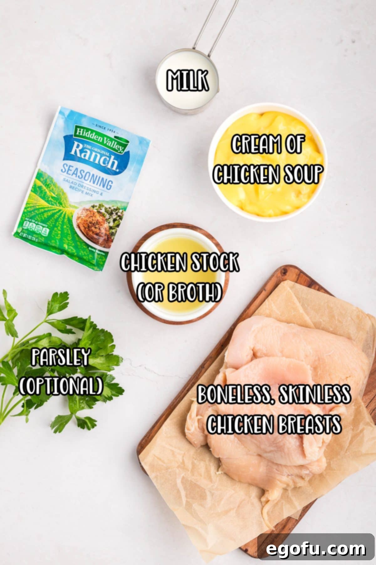 Creamy Ranch Slow Cooker Chicken 4 Ranch seasoning, milk, cream of chicken soup, chicken breast, chicken broth, and parsley laid out as ingredients for the recipe.