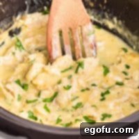 Creamy Ranch Slow Cooker Chicken 9 A wooden spoon in a Crock Pot full of Chicken and Ranch, ready to serve.