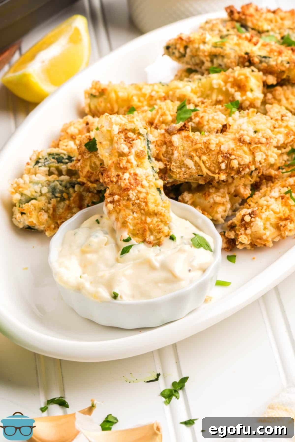 A Zucchini Fry being dipped in sauce.