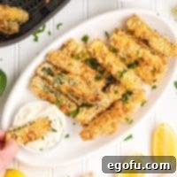 A hand holding a few Air Fryer Zucchini Fries, dipping one in sauce.