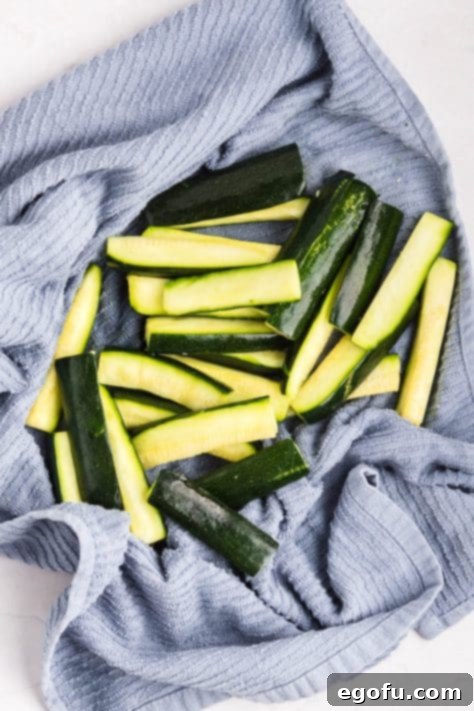 Zucchini being dried off with a kitchen towel.