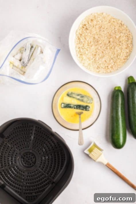 Zucchini sticks coated in flour being coated in egg wash.
