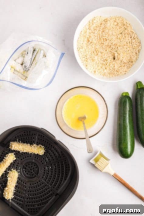 Zucchini sticks being added to an Air Fryer basket.