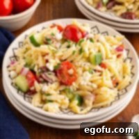 Closely looking down on a serving bowl full of Orzo Salad.