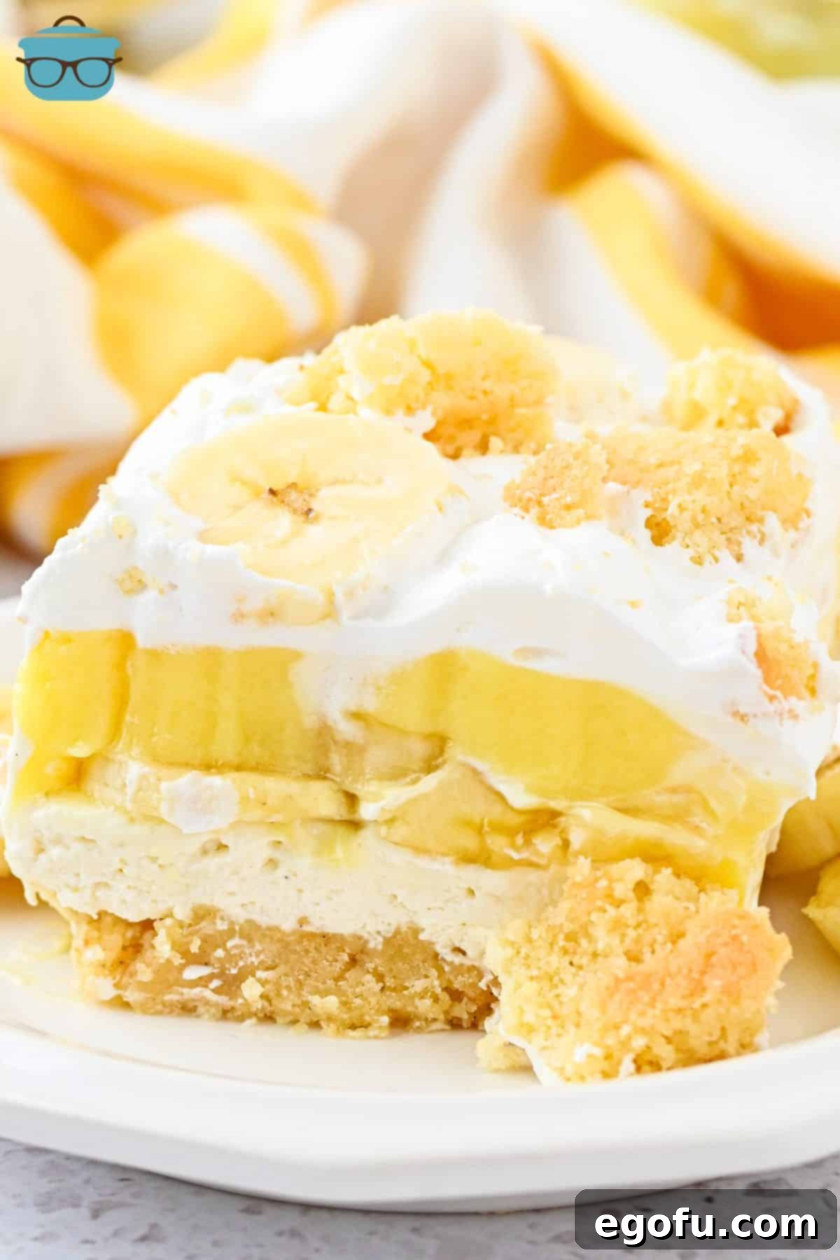 An overflowing slice of Banana Pudding Layered Dessert, showcasing its distinct layers and creamy texture.