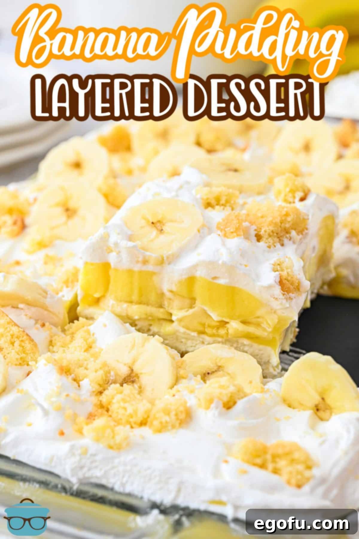 A baking dish with a perfectly scooped slice of Banana Pudding Layered Dessert being removed, revealing its layers.
