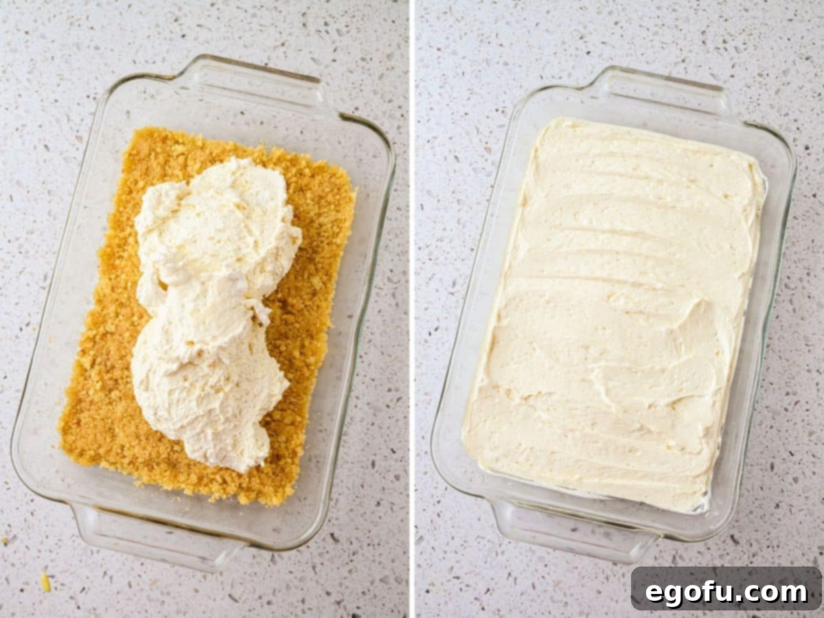 The cream cheese mixture being smoothly spread over the sugar cookie crumb crust layer in a baking dish.