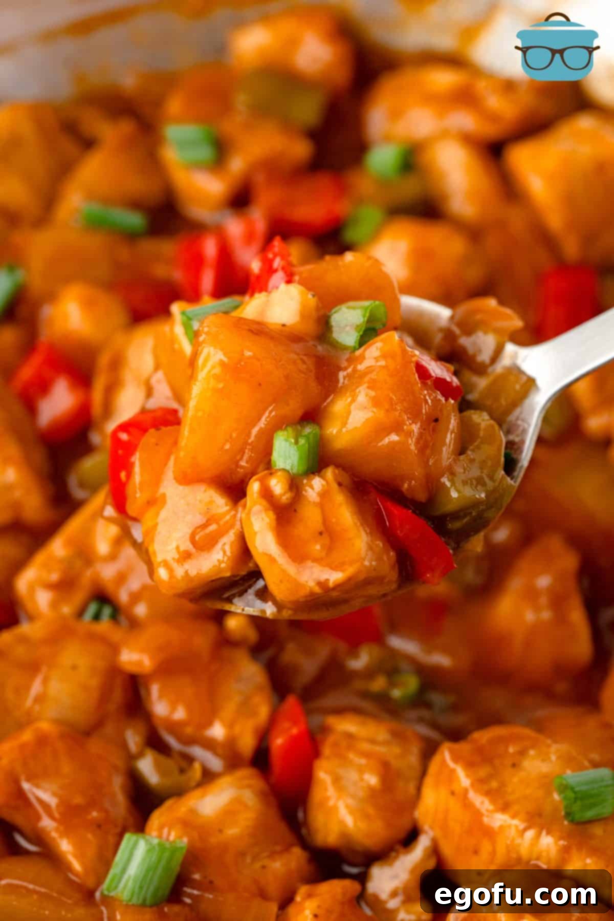 A fork holding a bite of Hawaiian Chicken, showcasing tender chicken, colorful bell peppers, and juicy pineapple.