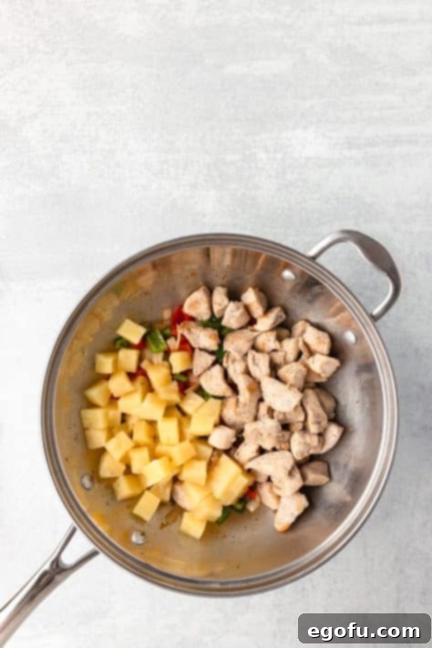 Cooked chicken and drained pineapple chunks added to the pan with vegetables.