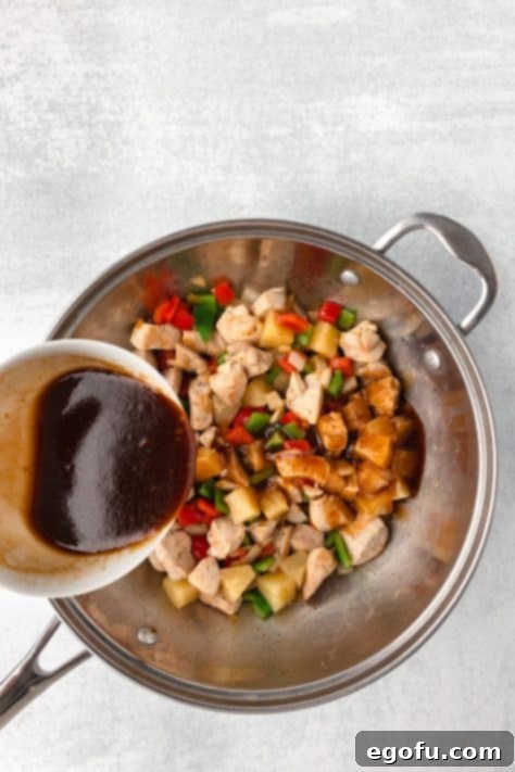 The Hawaiian sauce poured over the chicken, vegetables, and pineapple in a pan.