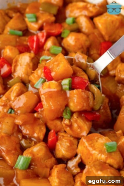 A scoop of Hawaiian Chicken being picked up, ready to be enjoyed with steamed rice.