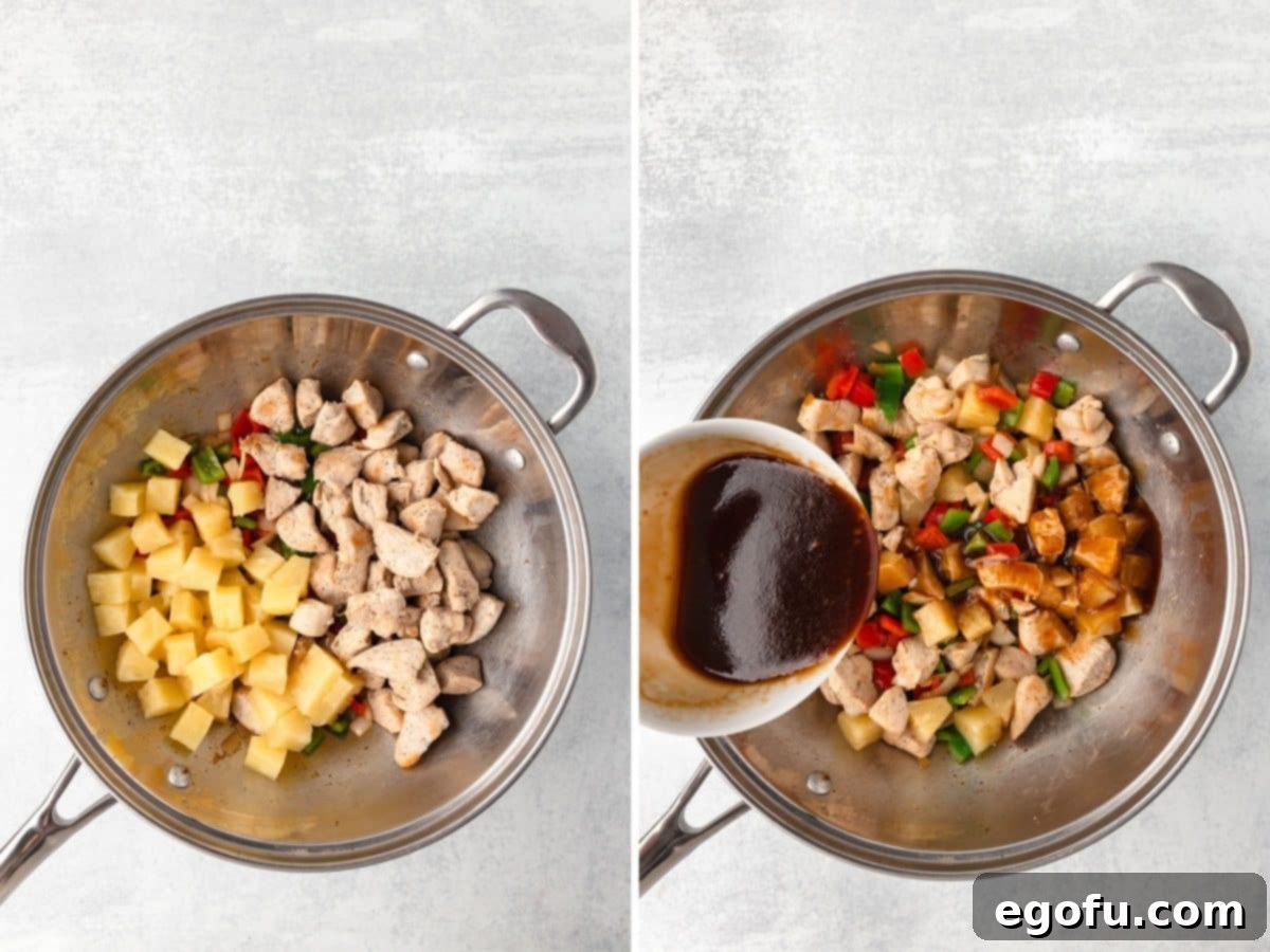 Cooked chicken pieces, pineapple chunks, and vegetables with the stir-fry sauce being poured over them.