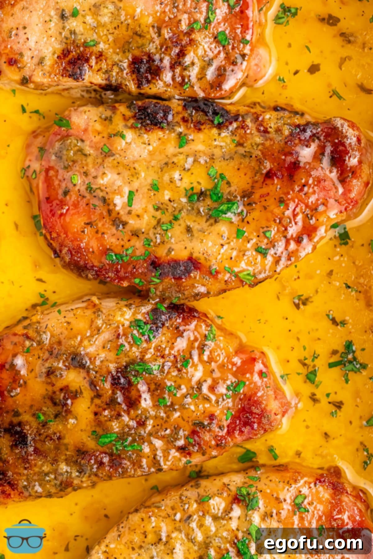 Golden Ranch Butter Pork Chops 7 Looking down on a few Ranch Butter Pork Chops in a baking dish with melted butter and sauce.