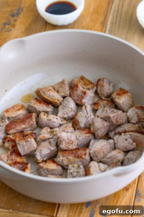 Tender Pork Bites in Rich Gravy 11 Pork bites searing in a hot skillet, developing a golden-brown crust.