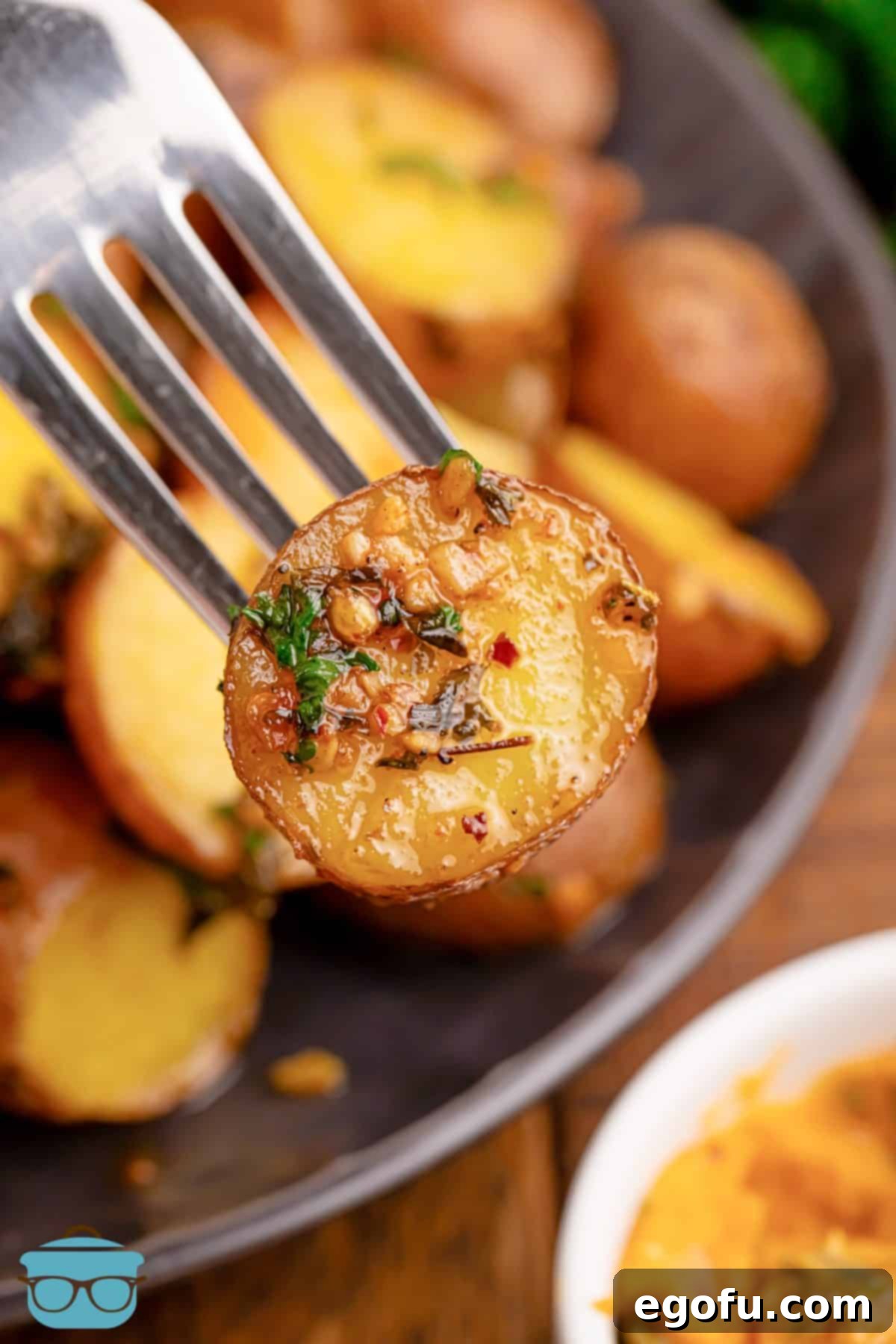Spicy Garlic Herb Roasted Potatoes 2 A fork holding a Cowboy Butter Potato bite, showcasing the golden-brown crispiness and herbaceous coating.
