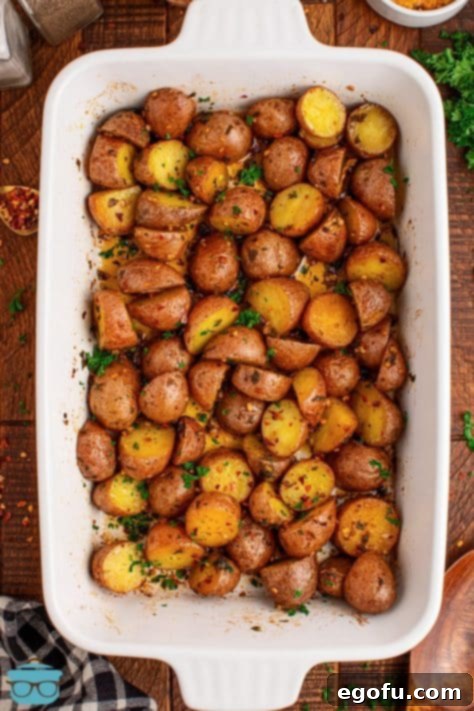 Spicy Garlic Herb Roasted Potatoes 11 Looking down on a baking dish full of finished Cowboy Butter Potatoes, garnished with fresh herbs.