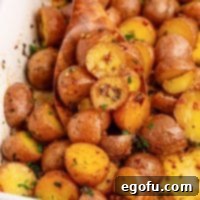 Spicy Garlic Herb Roasted Potatoes 8 Closely looking down on a serving dish of Cowboy Butter Potatoes, garnished with fresh herbs.