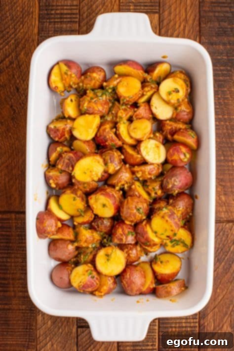 Spicy Garlic Herb Roasted Potatoes 10 Cowboy Butter coated potato pieces baking in a dish, half-roasted.
