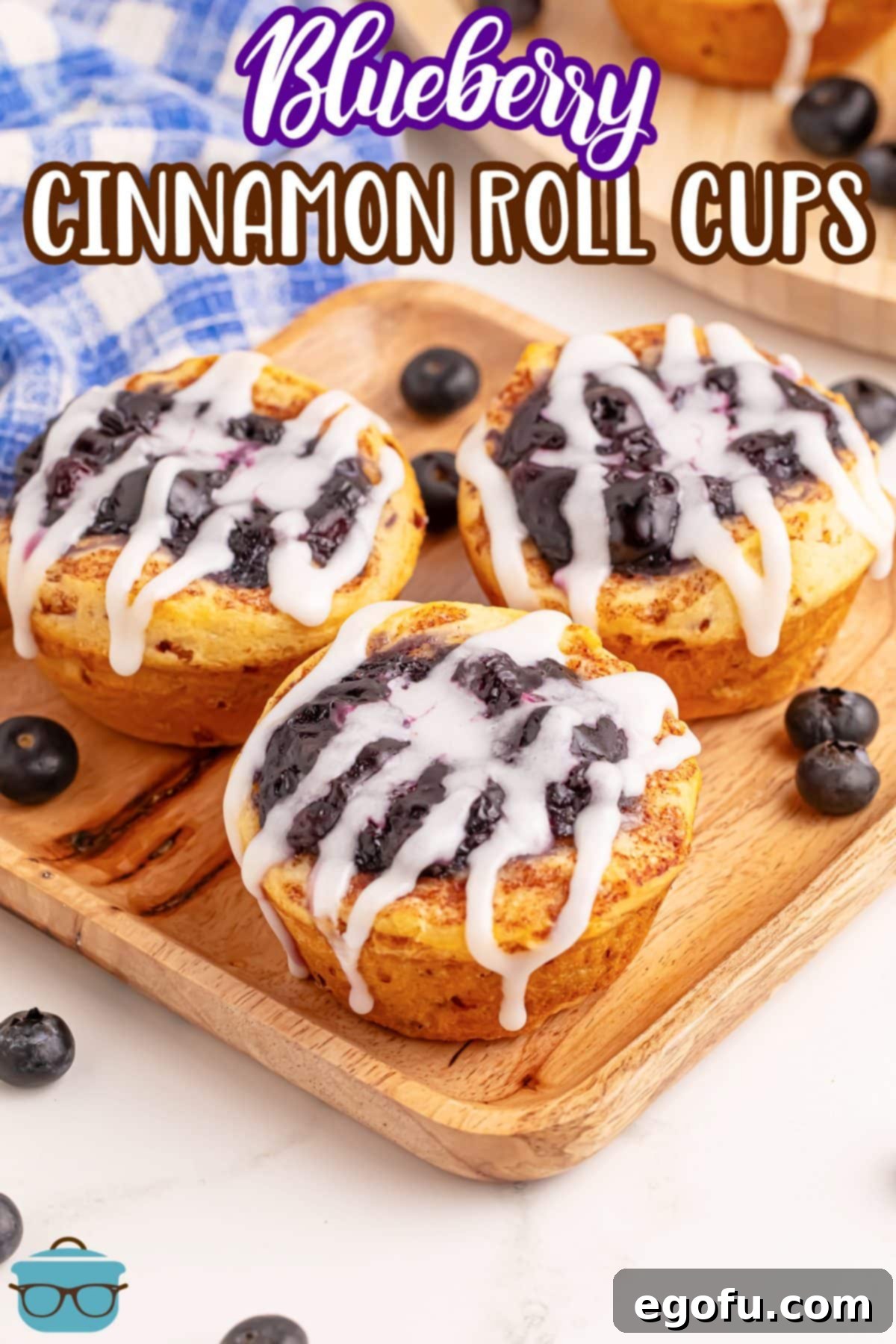 Blueberry Cinnamon Swirl Bites 3 A charming wooden serving plate artfully arranged with a few freshly baked Blueberry Cinnamon Roll Cups, garnished with icing.