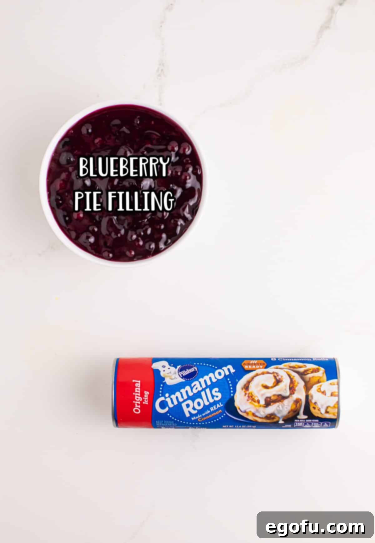 Blueberry Cinnamon Swirl Bites 4 A vibrant can of blueberry pie filling placed beside a tube of refrigerated cinnamon roll dough, ready for transformation into delicious cups.