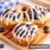 Blueberry Cinnamon Swirl Bites 7 Three Blueberry Cinnamon Roll Cups on a wooden serving plate, perfectly baked and glazed, ready to eat.