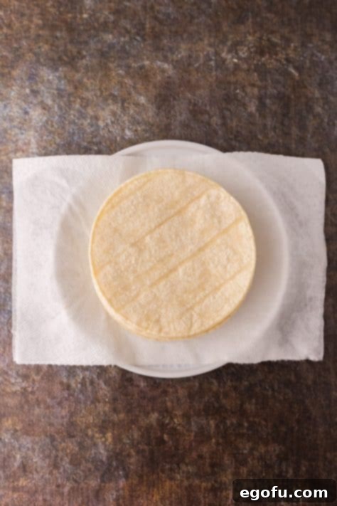 Warmed tortillas on a paper towel-lined plate.