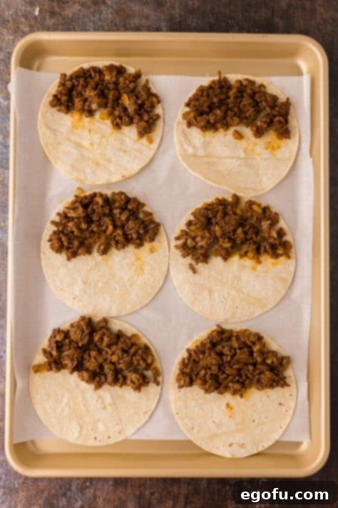 Ground beef in tortillas on a sheet pan.