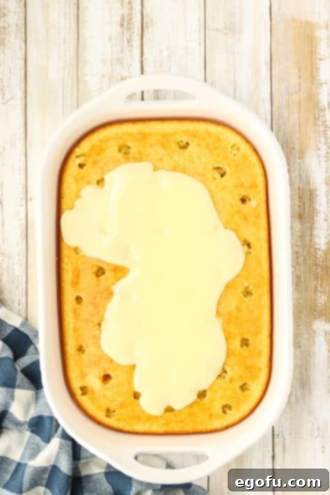 Espresso Kissed Tiramisu Poke Delight 14 Pudding being poured over a cake with holes.