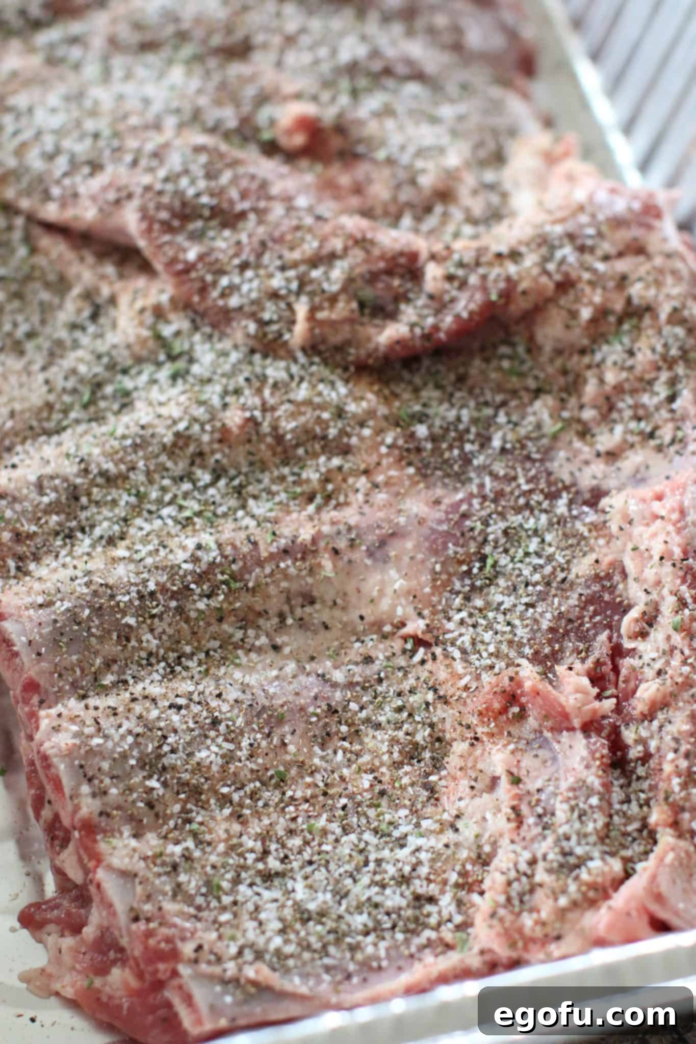 seasoned pork ribs shown in a disposable aluminum pan.