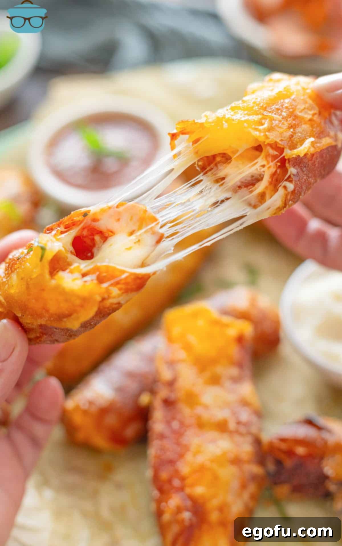 A Disney World inspired Pepperoni Pizza Spring Roll being broken apart with melty cheese.