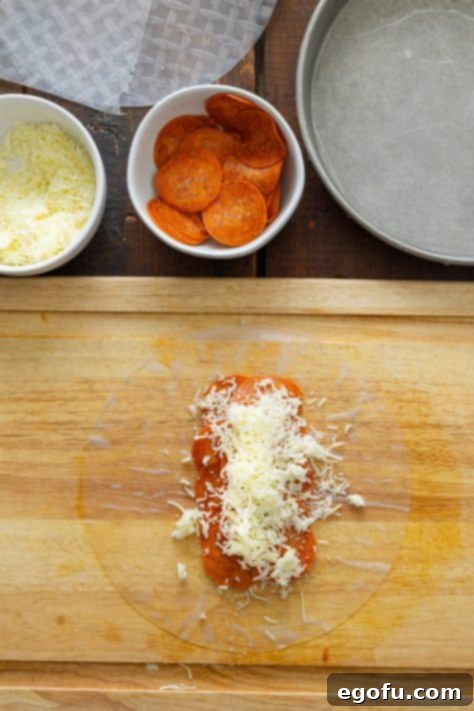 Layers of pepperoni and cheese on a spring roll wrapper.