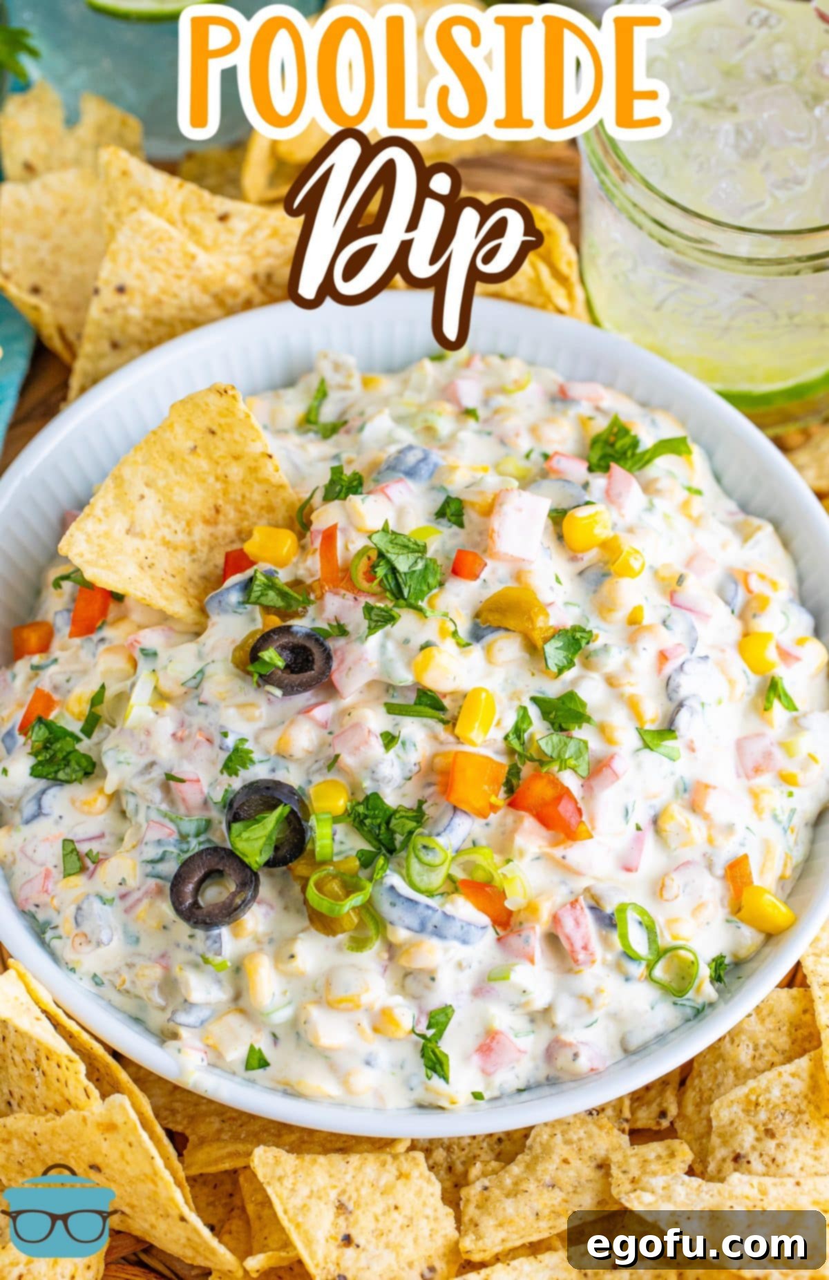 A vibrant bowl of Poolside Dip, garnished and ready to serve, accompanied by a generous selection of crispy chips on the side, perfect for sharing.