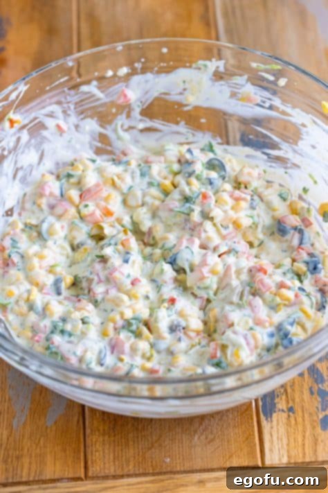 A bowl of Poolside Dip being actively mixed, showcasing the blending of creamy and colorful ingredients.
