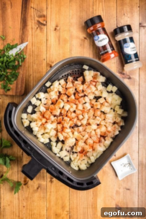 Smoky BBQ Chicken and Crispy Potato Skillet 12 Potatoes with seasoning in an Air Fryer basket.