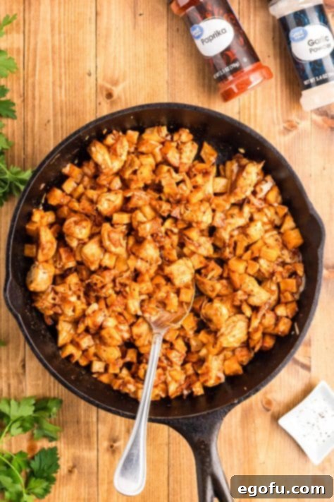 Smoky BBQ Chicken and Crispy Potato Skillet 18 A spoon stirring a Chicken and Potato skillet.