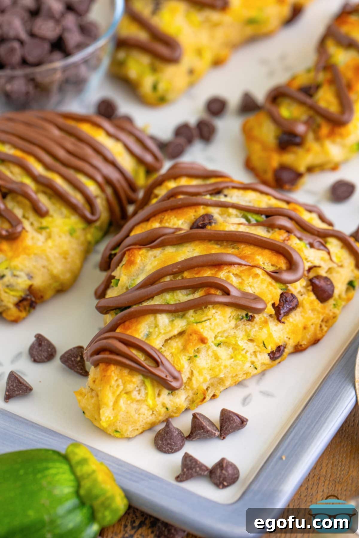 A parchment lined sheet with Chocolate Chip Zucchini Scones and some chocolate chips scattered around.