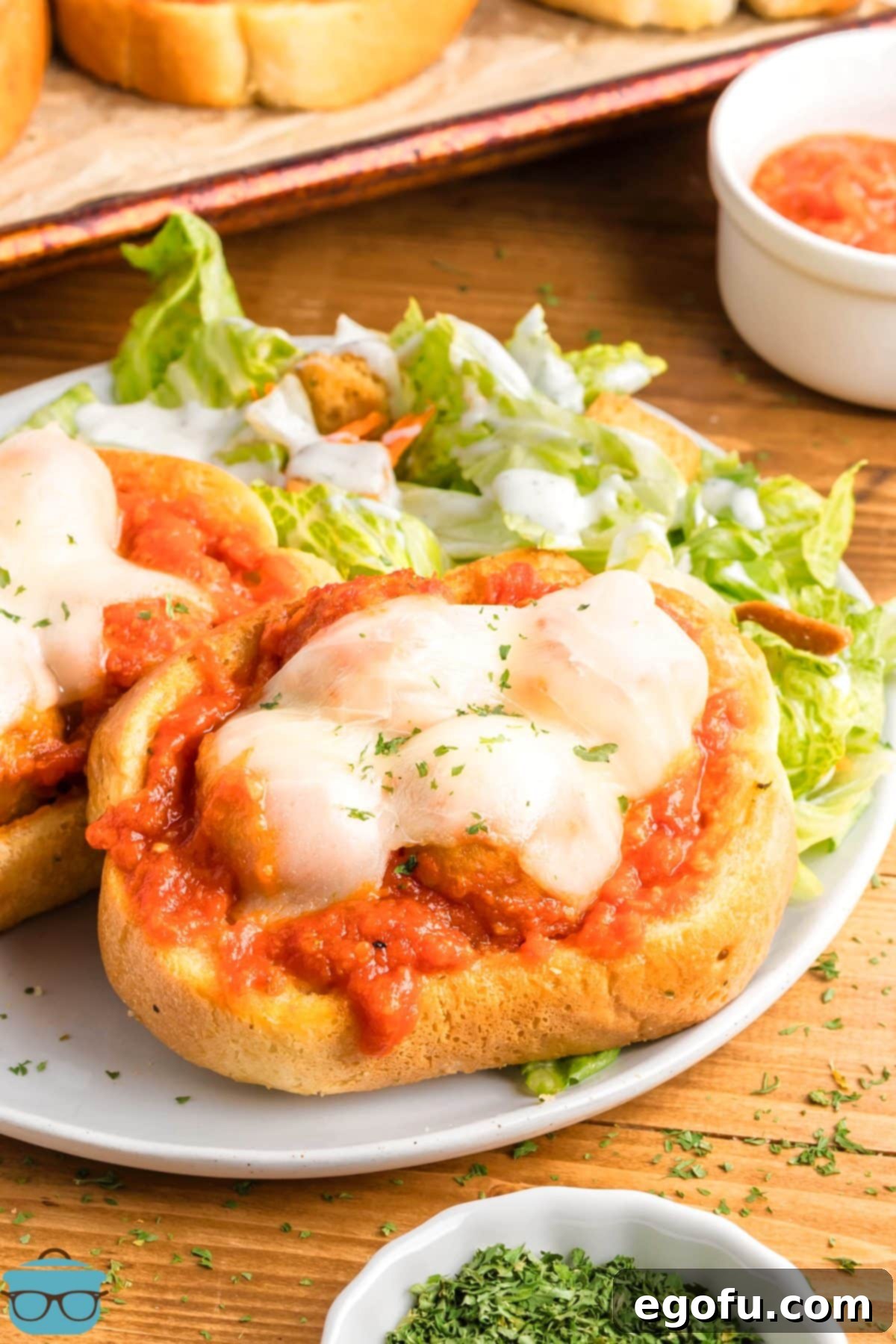 A Texas Toast Meatball Sub on a plate with caesar salad.