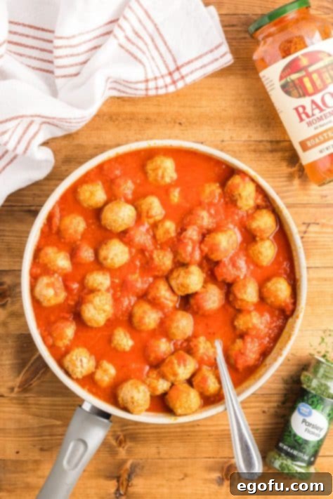 Meatballs simmering in red tomato sauce.