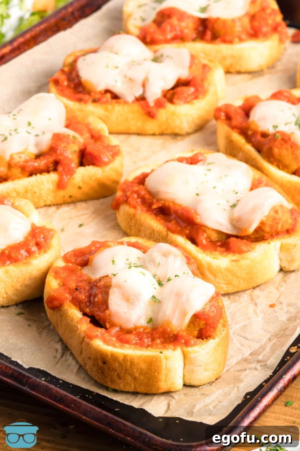 A couple pieces of Texas Toast Meatball Subs on a lined sheet pan.